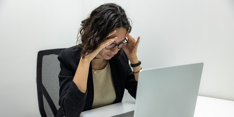 Mujer con dolor de cabeza mirando su ordenador